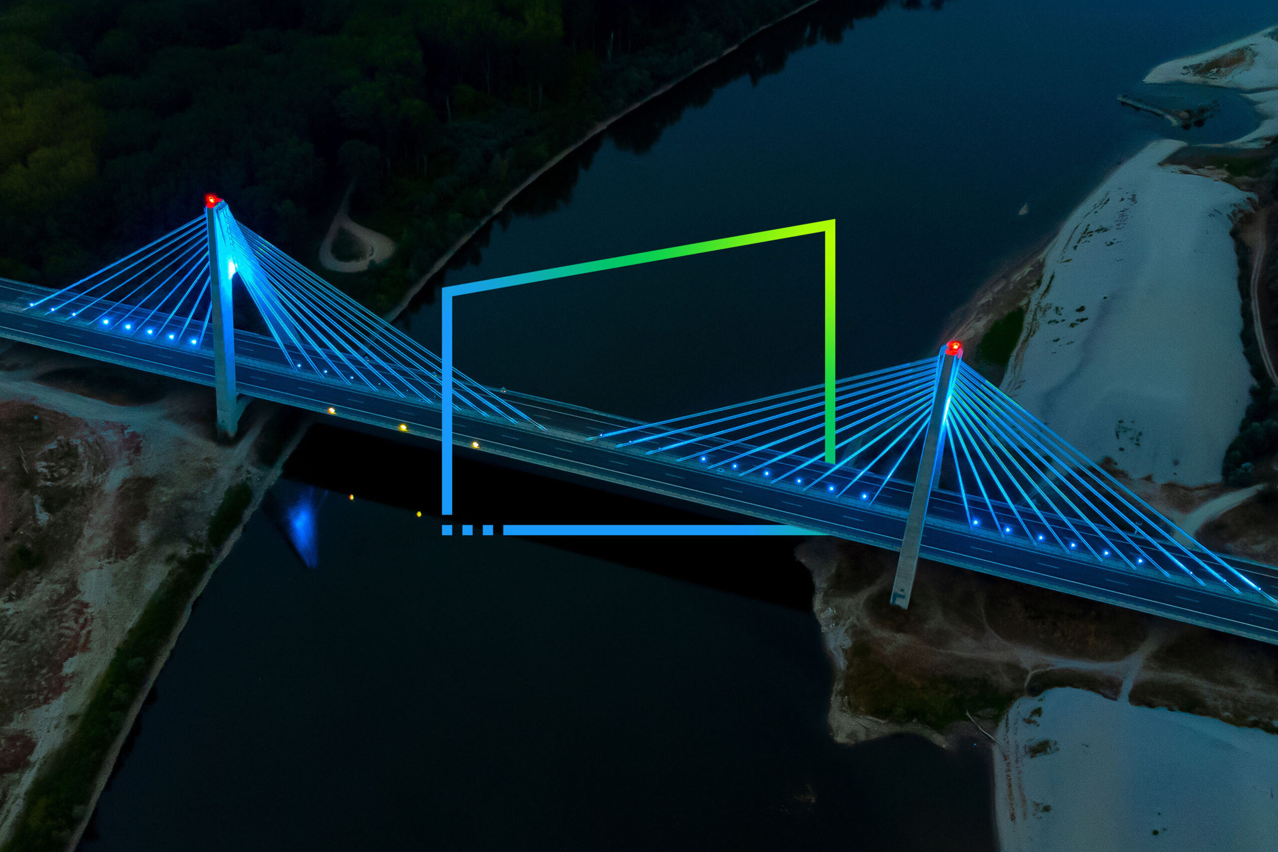Aerial view of the illuminated cable-stayed bridge over the dark river
